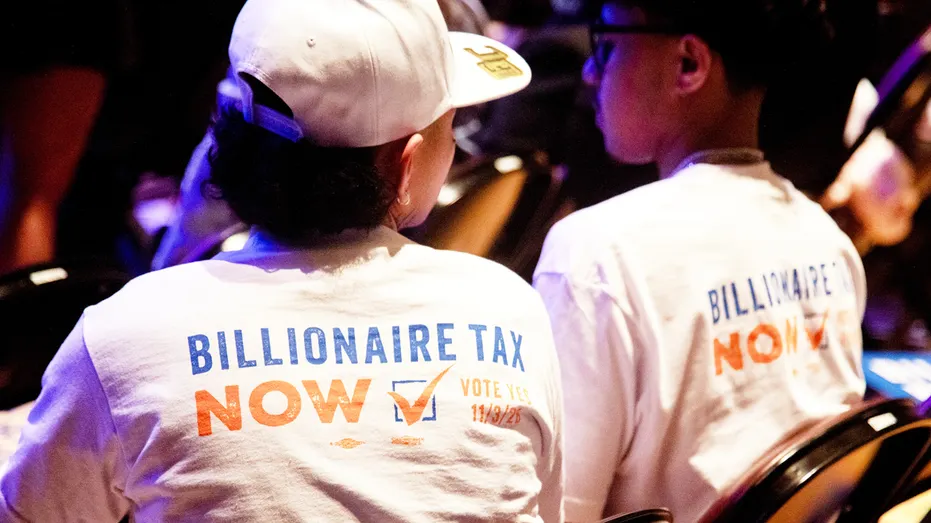 Attendees wear "Billionaire Tax Now" shirts