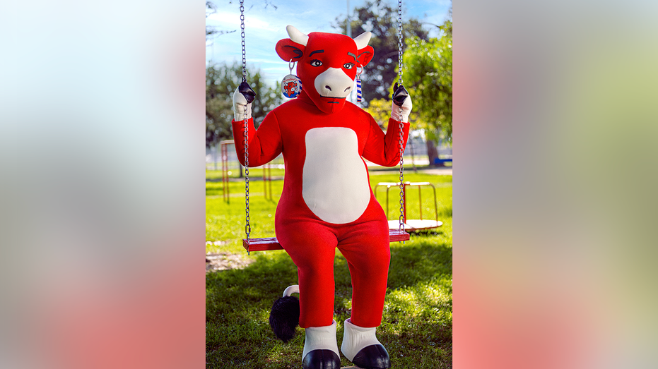 The Laughing Cow mascot sits alone on a swing with a serious expression