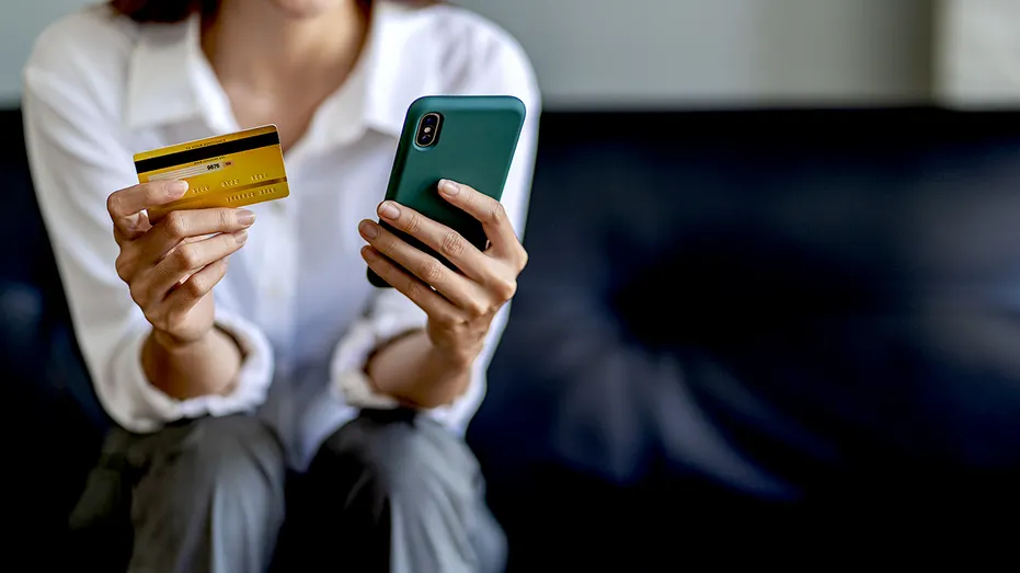 A person holding their credit card while on their phone