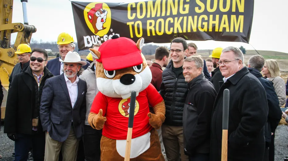 City officials standing next to Buc-ee's beaver mascot for photo at new construction location