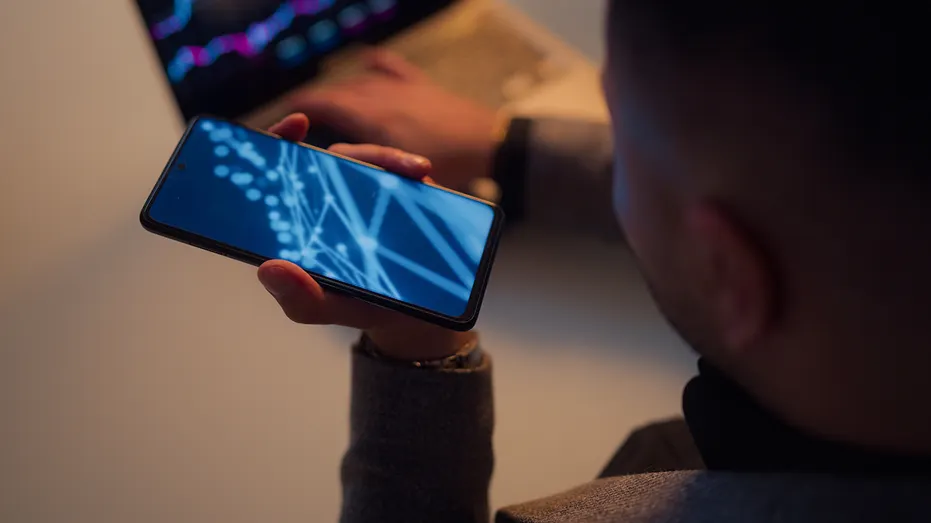 man uses phone with macbook