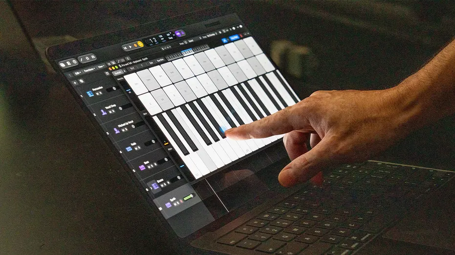A person touches a virtual piano keyboard on the display of Apple's new touchscreen MacBook Pro