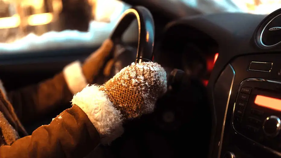 A drivers gloved hands on the steering wheel 