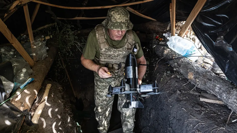 A Ukrainian soldier carries a drone to attack enemy drones.