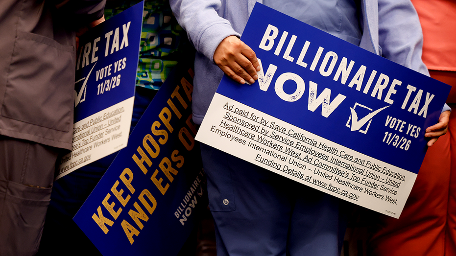 Supporters hold signs advocating for the Billionaire Tax Now coalition
